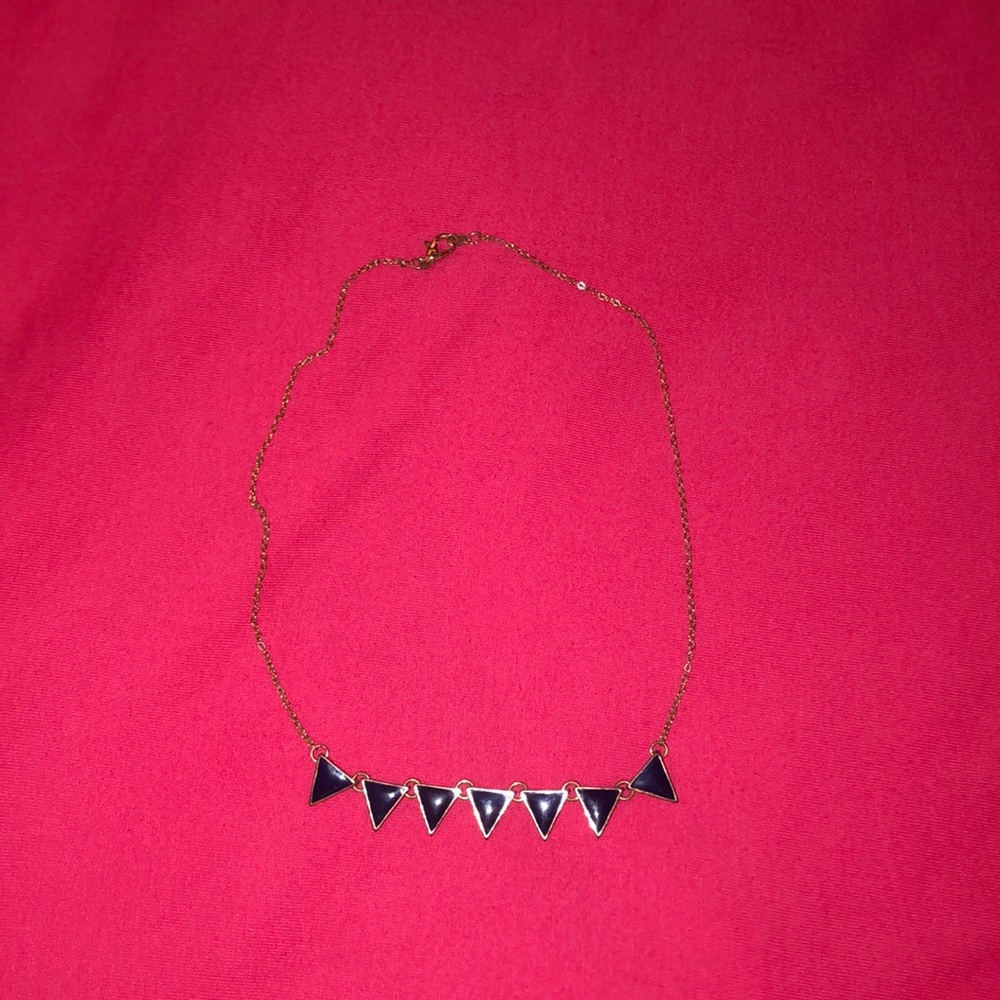 A gold necklace with navy triangles